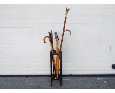 A stick stand containing a quantity of walking sticks and similar, two with silver mounted handles.