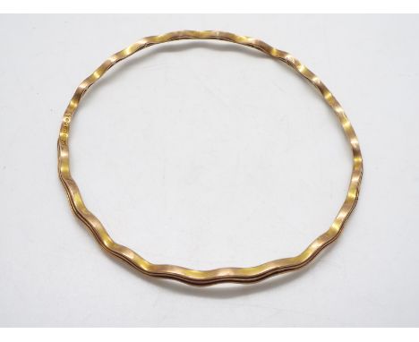 A 9ct gold bangle of undulating form, 7 cm (d), 9.5 grams.