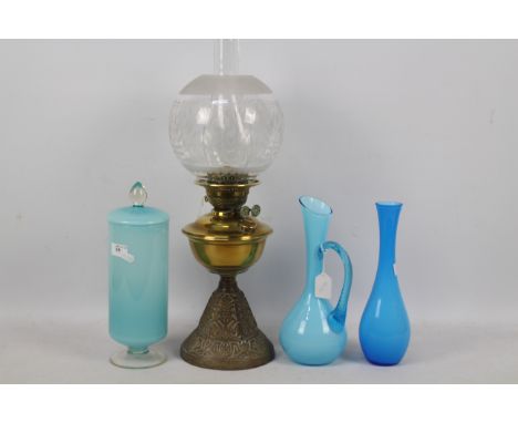 A brass and cast iron oil lamp, 54 cm (h) and three pieces of blue glassware. [4]