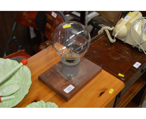 A large light bulb mounted on wooden plinth