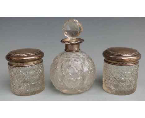 Three hallmarked silver topped cut glass dressing table pots and bottles comprising a globe shaped example and a pair, height