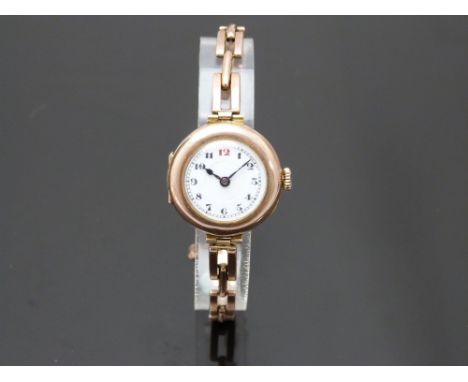 Edwardian 9ct gold ladies wristwatch with blued hands, black Arabic numerals, railroad minute track, stepped white enamel dia
