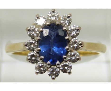 An 18ct gold ring set with an oval cut sapphire measuring approximately 1ct surrounded by diamonds, 5.38g, size R