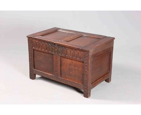 A SMALL 17TH CENTURY OAK COFFER, with two-panel lid and front, the front rails carved with lappets and conjoined scrolls. 49c