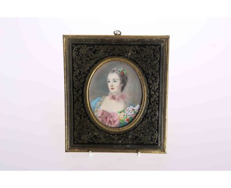 A PORTRAIT MINIATURE IN A BRASS FRAME, depicting a lady with flowers in her hair, the frame decorated with scrolling foliage.