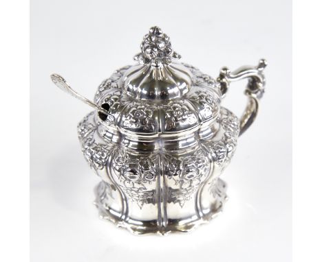 A Victorian silver mustard pot, pumpkin form with relief embossed floral decoration, floral finial, blue glass liner and orig