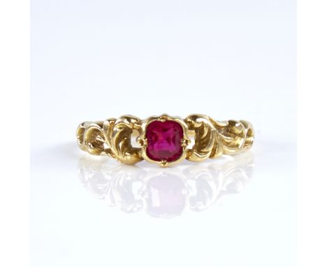 A late 20th century 18ct gold ruby dress ring, set with emerald-cut ruby and pierced foliate shoulders, setting height 6mm, s