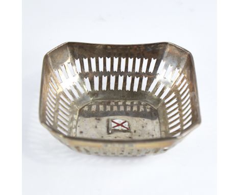 A small George V silver bon bon dish, canted square form with pierced gallery and central enamelled flag pennant emblem for C