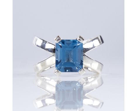 A modern handmade sterling silver blue topaz dress ring, set with emerald-cut topaz with cross style double shank, setting he