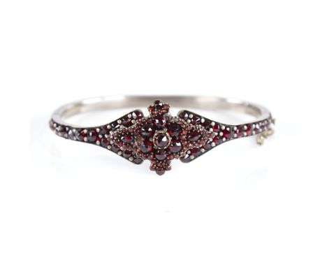 A Victorian faceted Bohemian garnet hinged bangle, gilt-metal settings, setting height 20.2mm, internal dimensions 56mm x 47m