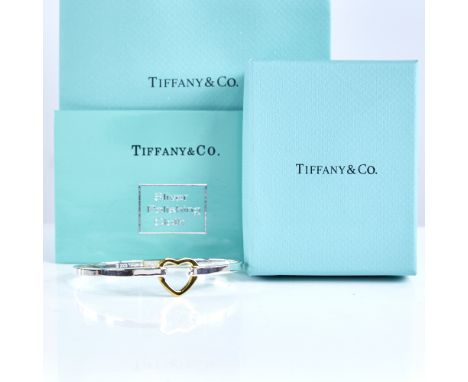 TIFFANY & CO - a modern sterling silver and 18ct gold heart bangle bracelet, heart height 16.3mm, internal dimensions 69mm x 