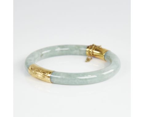A Chinese polished jade hinged bangle, with engraved 14ct gold mounts, band width 8.2mm, internal diameter 55mm, 37.9gExcelle