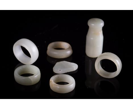 Five rings, a button and a jade mouthpiece China, Qing Dynasty, 19th Century Of varying styles and sizes in pale green jade. 
