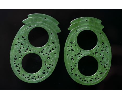 A pair of oval jadeite jade pendants China, 20th century Oval-shaped carved pendants in a fine bright green variety of jade. 