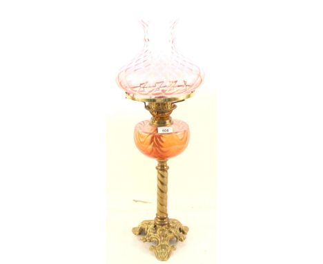 A brass oil lamp with pink glass bowl and shade