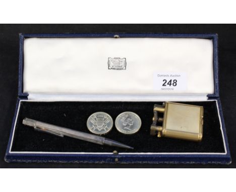 A gold plated Dunhill cigarette lighter with 1934 inscription, a silver propelling pencil plus two 2 pound coins