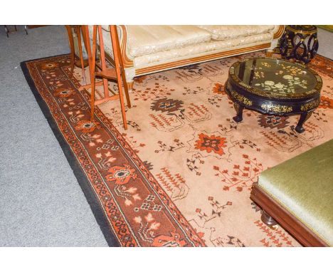 A machine made carpet of Ushak design, the pale camel field with columns of geometric devices and stylised plants enclosed by