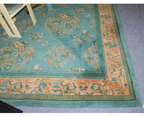 A machine made carpet of Chinese design, the mint green field of floral roundels enclsoed by meandering vine borders, 556cm b