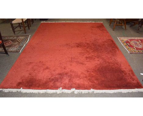 A Chinese carved carpet, the rust red field of scrolling vines, 360cm by 267cm