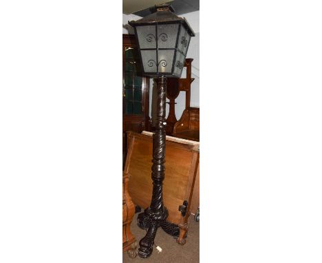 A Victorian mahogany standard lamp, the black metal lantern top above a carved and turned support, with three dolphin legs an
