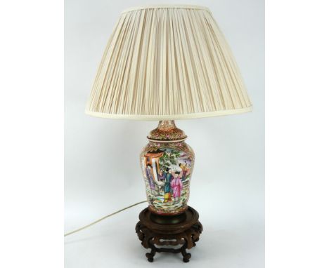 A Chinese porcelain baluster form lamp finely decorated in the famille rose style with panels depicting traditional scenes. C