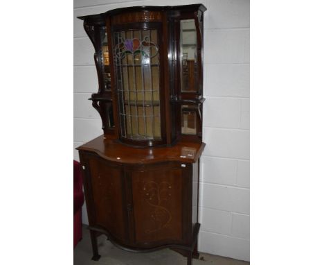 An Art Nouveau display cabinet , with inlaid decoration and coloured leaded glass display section flanked by narrow mirror an