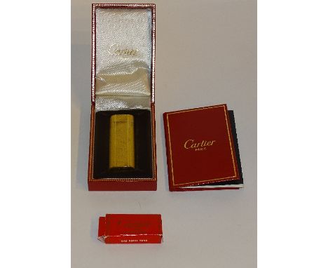 A Cartier of Paris Swiss made gold coloured lighter, engraved 84603 to underside, with boxed refill tank, booklets and guaran