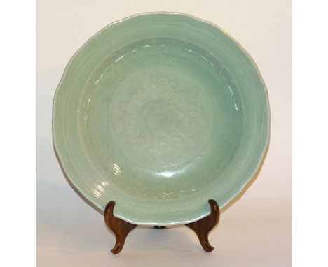 A Chinese celadon saucer dish circa 19th century, decorated with impressed lotus flower and leaf, with a glazed brown swirl u