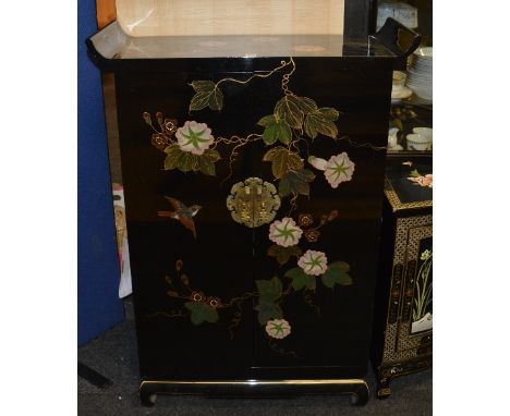 A modern Chinese black lacquered cupboard, with sleigh style top above two doors decorated with colourful panel of birds and 