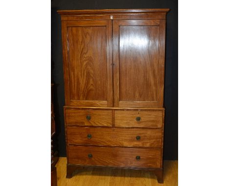 A Georgian mahogany linen press on chest circa early 19th century, with moulded cornice above two panelled doors enclosing sh
