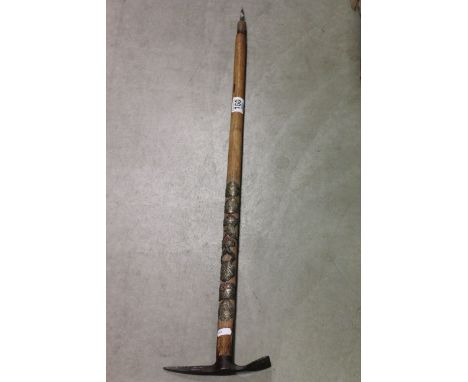 A vintage alpine ice axe walking stick decorated with metal badges to stem