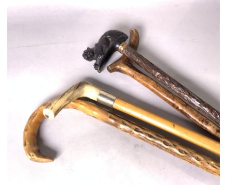 AN EARLY 20TH CENTURY BLACK FOREST CARVED WALKING STICK (4)The pommel formed as a dog 91cm long and three further