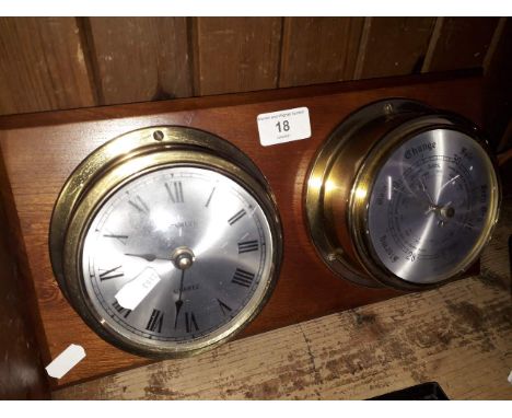 A brass cased clock and barometer mounted on a board 