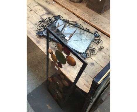 A metal framed mirror and a piece of metal wall art 