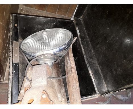 A metal box containing car headlight, axe and saw 