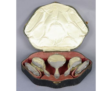 A George V silver-backed dressing table set of curved &amp; reeded outline, comprising a hand mirror, pair clothes brushes, p