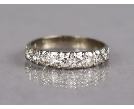 A half-hoop ring set nine graduated cubic zirconia to a white metal shank marked “18ct”, size T. (3.8g).