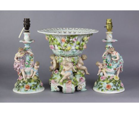 A Dresden porcelain large pierced &amp; floral-encrusted basket dish on cherub supports, 12” high x 12” wide, &amp; a pair of