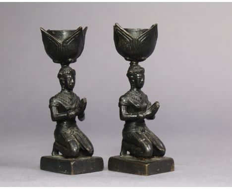 A pair of eastern bronze candle holders on figural columns &amp; plinth bases, with lotus-form sconces, 5” high.
