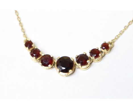 A 9ct gold fine-link necklace set seven graduated round-cut garnets (5g gross; the chain with break to ring-bolt fastener).