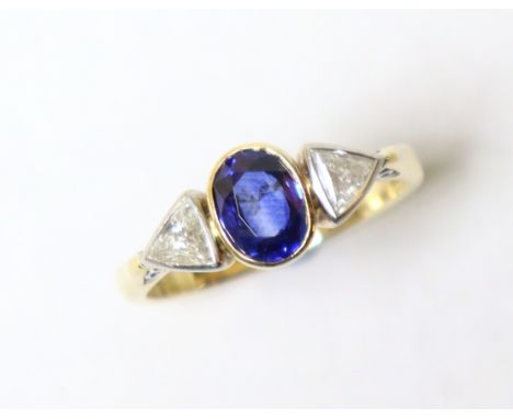 A sapphire &amp; diamond ring, the oval-cut sapphire approx 0.8carat, flanked by a triangular-cut diamond either side, set to