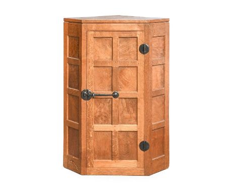 Workshop of Robert Mouseman Thompson (Kilburn): An English Oak Hanging Corner Cupboard, with panelled door enclosing three fi