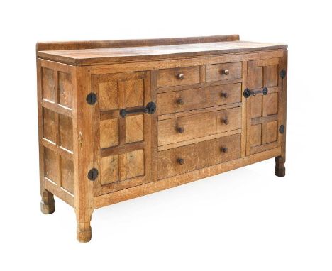Robert Mouseman Thompson (1876-1955): An English Oak 5'3" Panelled Sideboard, 1930s, with raised upstand above a central bank