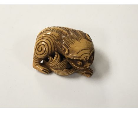 A caved and stained Ivory Netsuke in the form of a temple dog. 3cm.