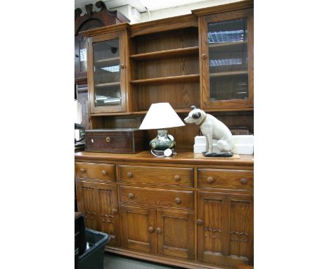 An Ercol type dining room dresser, the base having three cupboards of various size and four drawers, the top having two cupbo