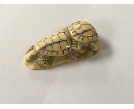 A Japanese carved Ivory Netsuke of the Meiji period in the form of two tortoises on a rock signed base.