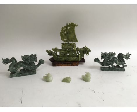 A collection of jade carvings including a large ship approximately 10x10 inches on the stand, two dragons and three smaller f
