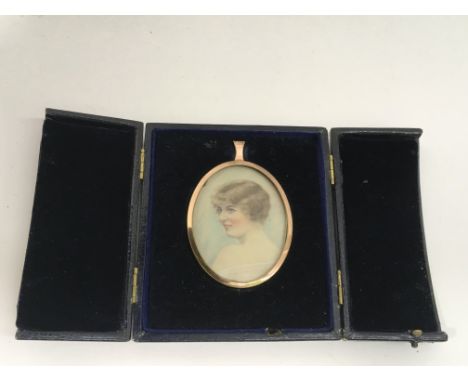 An oval painted portrait miniature of an Art Deco girl, possibly on ivorene, in yellow metal mount and presentation case