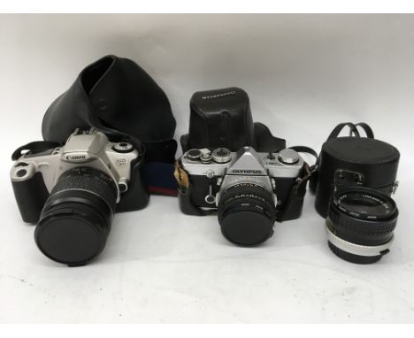 A collection of cameras and accessories including an Olympus and canon SLR together with various lenses and a light meter.
