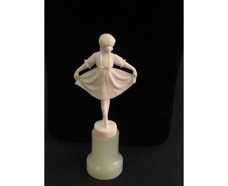 A small carved ivory figure of a young girl holding her skirt outstretched, mounted on marble base.In the manner of Ferdinand